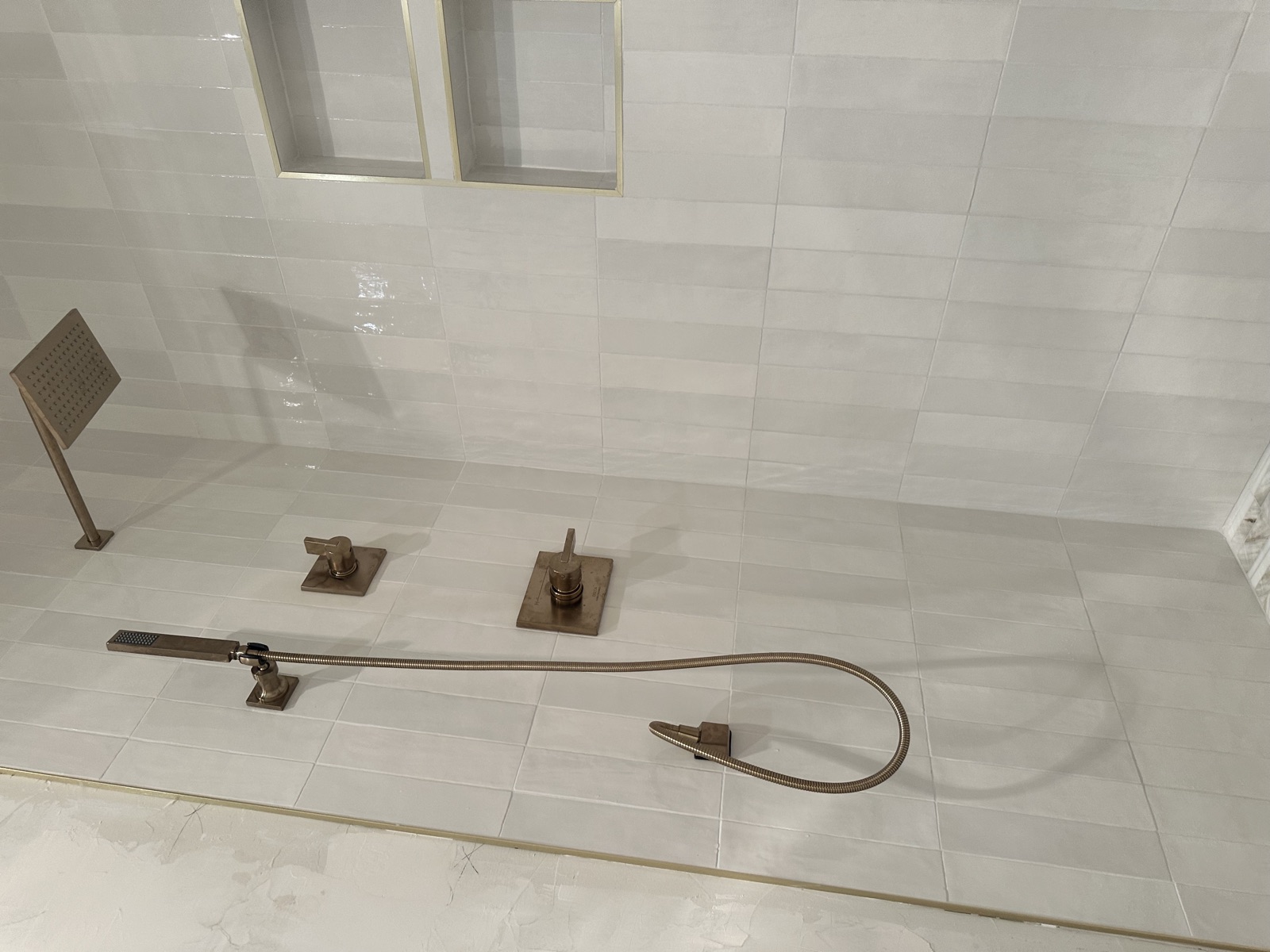 Tiled tub deck with brushed-bronze fixtures and a recessed niche